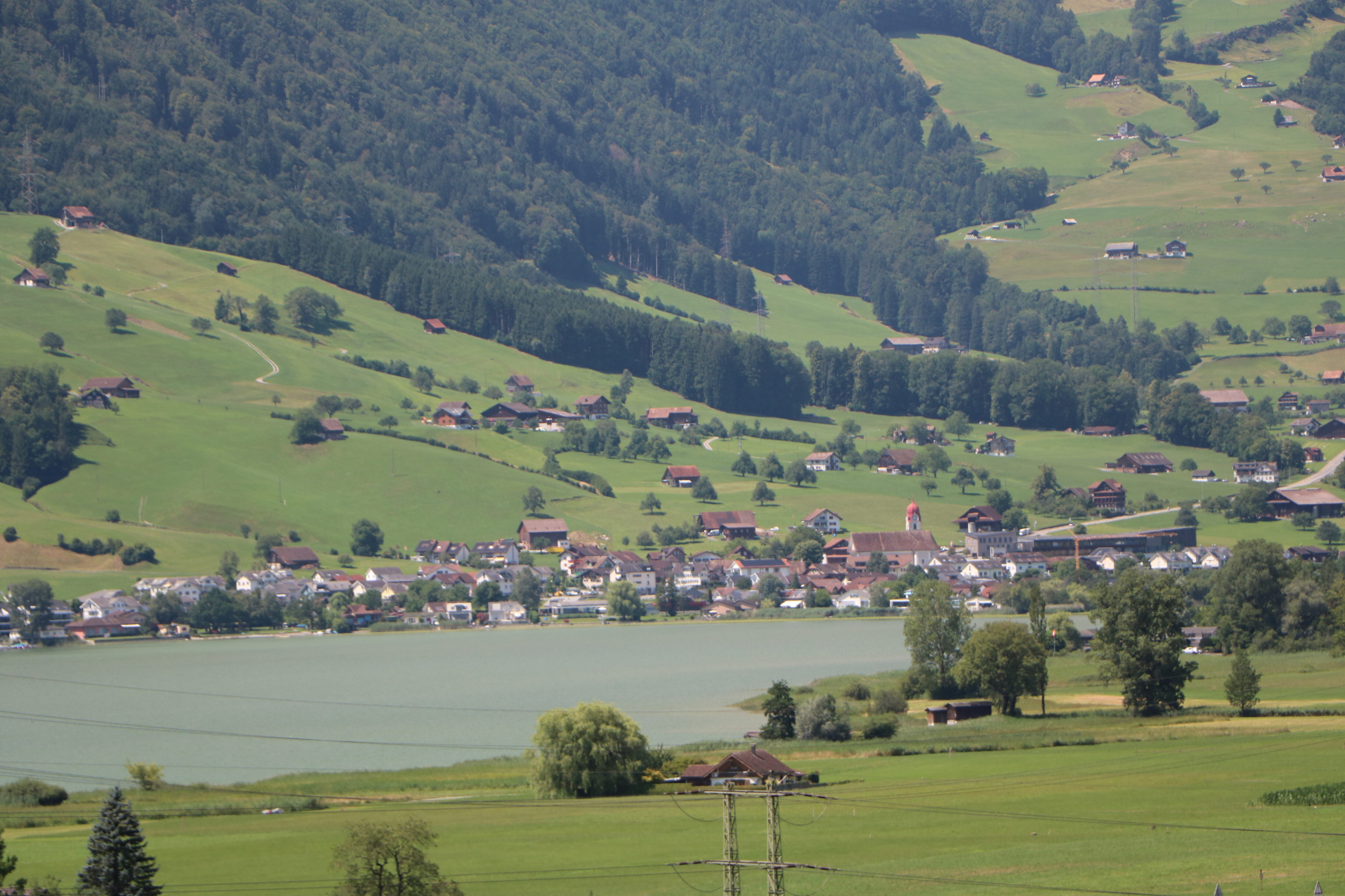Foto von Dorf mit See, Wiesen und Wald