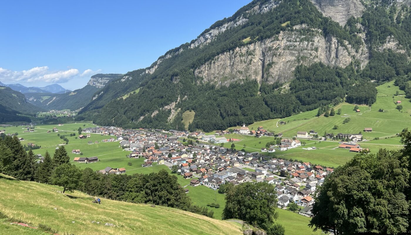 Foto von Dorf mit Wiesen und Berge